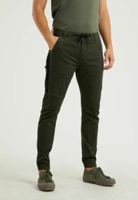 Pantalons cargo verts ajustés, dotés d'une taille à cordon de serrage, de poches latérales et de panneaux noirs contrastants sur les côtés.