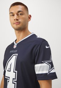 Tengerészek (Navy) focimez, lélegző anyagból készült, ezüst díszítésekkel, egy nagy fehér 4-es számmal és a "COWBOYS" csapatnévvel a mellkasán.