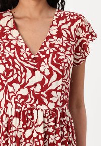 Vestido de estampado floral rojo con escote en V, detalles de botones y mangas cortas con volante. Hecho de un tejido ligero con un acabado texturizado.