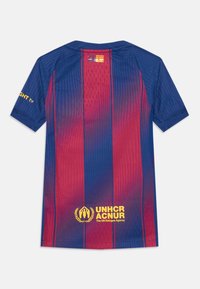 Blå og rød stripete fotballskjorte med ribbet tekstur, med en gul logo og detaljer. Kragen er i crew-stil med korte ermer.