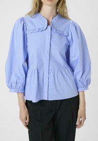 Blusa a righe blu chiaro con colletto arruffato corto, maniche a sbuffo e vita arricciata. Il materiale sembra liscio con righe verticali e orizzontali.