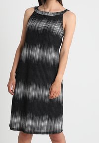Schwarzes und weißes ärmelloses Kleid mit einem Verlaufsmuster, ausgestattet mit einer gerippten Textur und einem weiten Ausschnitt. Mittellanges Design.
