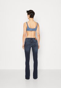 Tumman pesun farkkuhaalari, jossa on leveä lahje, keskikorkea vyötärö ja takataskut. Yhdistetty vaaleansiniseen farkkutoppiin, jossa on leveät hihnat.