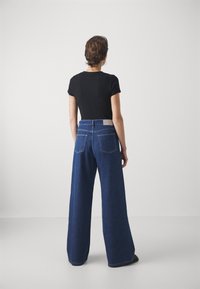 Jeans med vida ben i mörk tvätt, med hög midja, klassisk femficksdesign och en grå läderlapp bak.