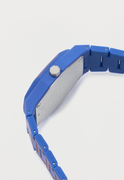 Μπλε ψηφιακό ρολόι χειρός με ορθογώνιο καντράν, ασημένια πίσω πλάκα και τμηματικό λουράκι με πορτοκαλί γραμμές.