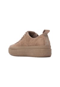 Zapatillas de deporte en tono beige con un upper de tela texturizada, cordones planos y una suela gruesa. Presentan una lengüeta en el talón y un logotipo discreto en el lateral.