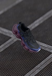 Chaussure de sport noire avec une tige texturée, semelle rembourrée violette et magenta, deux accents bleus et un logo avec "MERRELL."