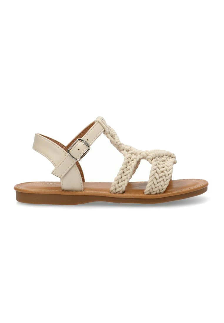 Sandalias trenzadas beiges con suela plana, que presentan un diseño de correas trenzadas y un broche lateral para ajuste. Material sintético suave.
