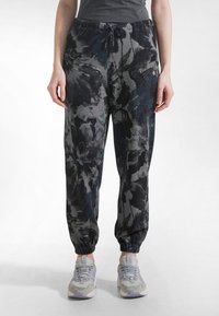 Mustat kukkakuvioiset collegehousut, joissa on nyöritysvyötärö ja joustavat resorit. Valmistettu pehmeästä kankaasta, yhdistetty vaaleanharmaisiin tennareihin.