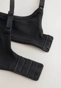 Sorte BH-stropper i stof med justerbare kroge og løkker på en lys overflade, der viser detaljer om den justerbare lukning.