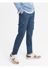 Granatowe spodnie cargo wykonane z rozciągliwego materiału, z kieszeniami na zamek, w połączeniu z wielokolorowymi trampkami z zamszowymi i siateczkowymi akcentami.