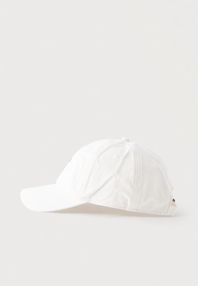 Casquette de baseball blanche réglable posée sur le côté avec une visière courbée sur un fond clair uni.