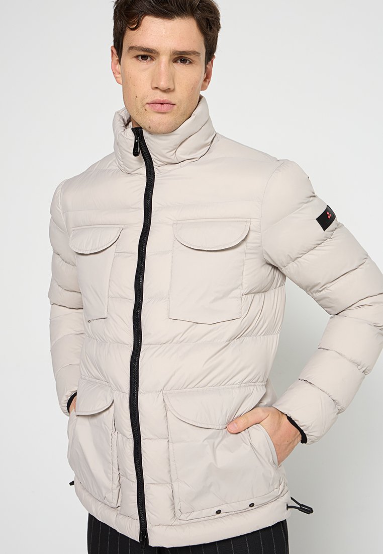 Giacca puffer beige chiaro con colletto alto, zip frontale, due ampie tasche a pattina e un discreto logo sulla manica.