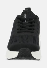 Black athletic shoe with a textured upper, featuring a white sole and detailed mesh panels for breathability. Includes black laces and logo.