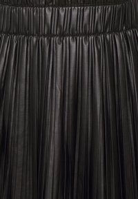 Jupe plissée noire en matériau lisse et brillant, avec une taille élastique, présentant des plis verticaux qui créent une apparence texturée.