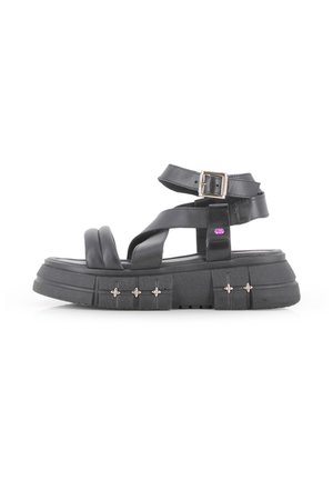 Sandalias de plataforma negras con tiras cruzadas, correa de tobillo ajustable y acentos de hardware plateado. Hechas de material sintético con suela texturizada.