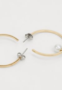 Orecchini a cerchio dorati con un design curvo, caratterizzati da un orecchino decorato con una perla bianca e hardware argentato per una chiusura sicura.
