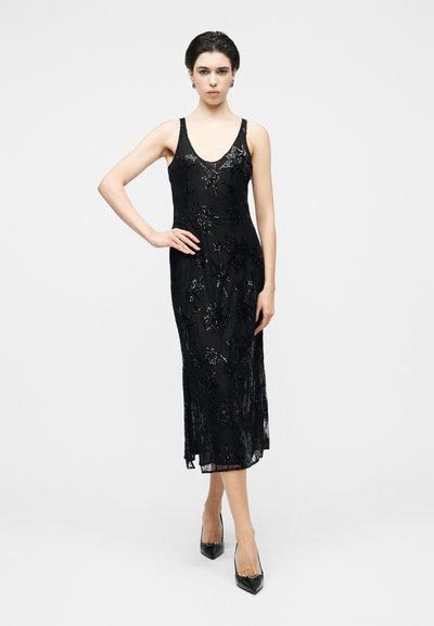 Robe noire sans manches avec un décolleté en V profond, ornée de perles florales délicates, une silhouette cintrée et un ourlet au-dessous du genou.