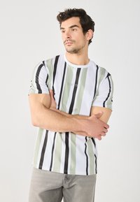 Camiseta a rayas blanca y verde con acentos negros, cuello redondo y mangas cortas. La tela parece suave con un ligero brillo.