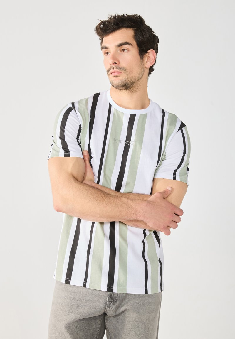 Camiseta a rayas blanca y verde con acentos negros, cuello redondo y mangas cortas. La tela parece suave con un ligero brillo.