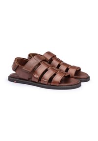 Braune Leder-Sandalen mit vier breiten Riemen, offener Zehenpartie und verstellbarem Rückriemen, auf einer flachen schwarzen Gummisohle.