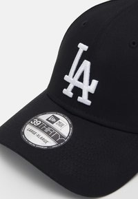 Μαύρο καπέλο μπέιζμπολ με λευκό κεντημένο λογότυπο "LA". Διαθέτει καμπύλη γείσο και υφή υφάσματος. Η ετικέτα δείχνει μέγεθος "Large-XL."