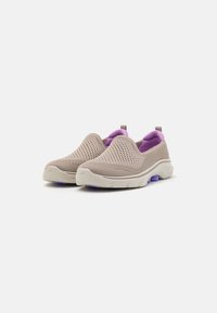 Sapatos slip-on feitos de malha beje respirável com um colarinho acolchoado roxo e uma sola branca grossa com um detalhe roxo.