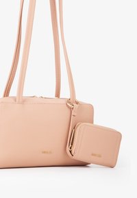 Borsa rosa strutturata con manici doppi e un portafoglio con zip staccabile, caratterizzata da accessori in oro e un design semplice e rettangolare.