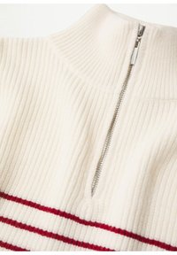 Maglione a coste crema con zip parziale in argento e due strisce orizzontali rosse vicino al fondo.