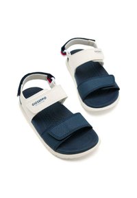 Sandalias en tonos marino y blanco con material texturizado, correas ajustables y suelas de goma. Presentan el logotipo en la correas superior.