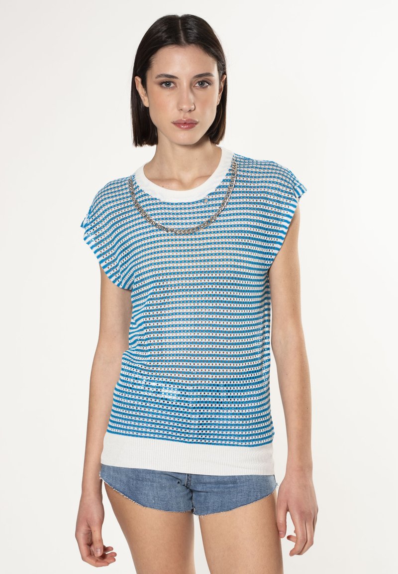 Top de punto a rayas azul y blanca con mangas cortas, con un escote redondo y detalles metálicos alrededor del cuello. Pantalones cortos de mezclilla.