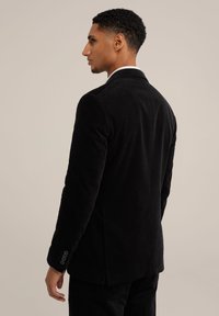 Zwarte corduroy blazer met een getailleerde pasvorm, voorzien van een notch lapel, enkele split en afwerking met vier knopen op de mouwen. Gladde textuur en gestructureerd ontwerp.