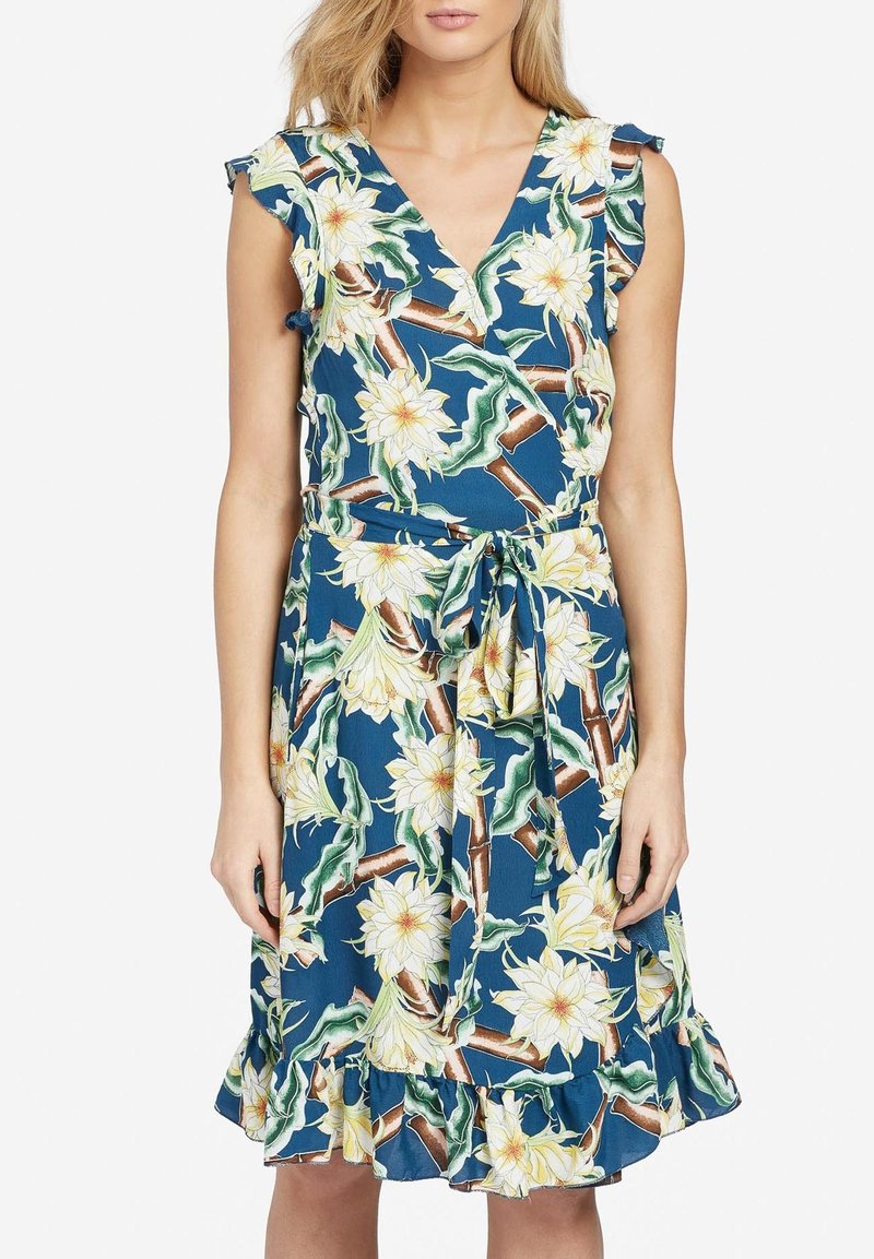 Ärmlös V-ringad blommig klänning med blå bakgrund, vita och gula blommor, gröna blad, volangkant och knytbart midjebälte.