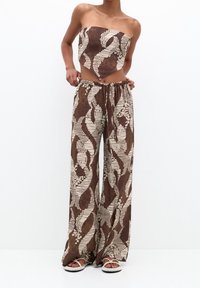 Completo a due pezzi marrone a fantasia con top senza spalline e pantaloni a gamba larga con vita regolabile. Tessuto morbido con un design astratto.