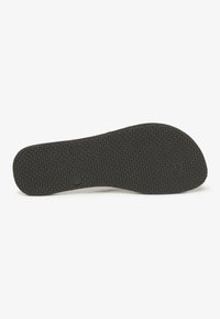 Semelle de chaussure en caoutchouc noire avec une surface texturée et à motifs, dotée de deux indentations circulaires, conçue pour l'adhérence et la durabilité.