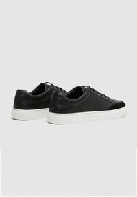 Sneaker nere in pelle con punta in suede, suola in gomma bianca e lacci rotondi, caratterizzate da una superficie liscia e un design minimal.