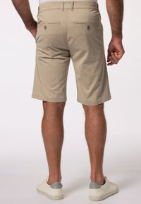 Beige shorts van lichtgewicht stof, met een vlakke voorkant, twee achterzakken met knopen en een zoom net boven de knie.