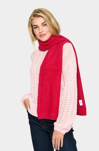 Rød tørklæde lavet af blødt stof, som draperer omkring halsen. Kombination med en lys pink strikketrøje med et tekstureret mønster.