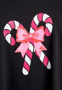 Svart t-shirt med en grafisk design av två röda och vita godistrutar bundna med en stor rosa rosett.