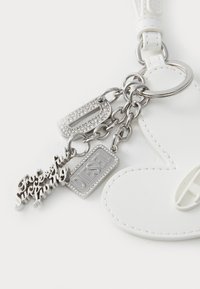 Porte-clés en cuir blanc en forme de cœur avec quincaillerie en argent, comportant plusieurs charms incluant des étiquettes scintillantes et le mot "DIESEL".