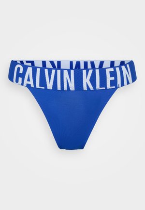 Blue Calvin Klein thong with a wide elastic waistband featuring white logo text. Smooth fabric, triangular shape, minimal coverage design.