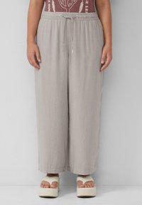 Lichtgrijze wijde broek met een elastische tailleband en een trekkoord. Het materiaal lijkt zacht en lichtgewicht, met een subtiele textuur.