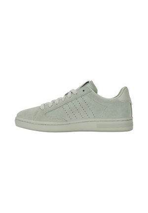 Zapatilla baja de ante verde claro con suela plana, franjas perforadas en los laterales y cordones a juego sobre fondo blanco.