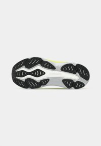 Laufschuhsohle mit schwarzen Gummilaufflächen, weißer Zwischensohle und dem "saucony"-Logo zentral auf einem grauen und neongelben Hintergrund.