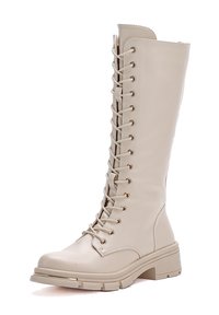 Stivali color beige alti fino al ginocchio realizzati in pelle vegan liscia. Presentano occhielli dorati, stringatura frontale e un tacco spesso per maggiore durata e supporto.