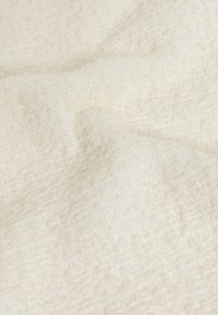 Texturovaná krémová látka s tkaným vzorem, která má měkký, mírně pomačkaný vzhled a nepravidelné vlákna po celé ploše.