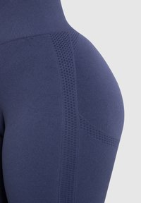 Granatowe legginsy z wysokim pasem, z teksturowanym wzorem oraz oddychającymi siateczkowymi wstawkami po bokach.