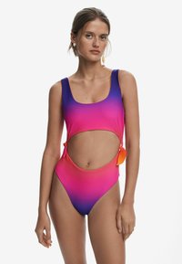 Maillot de bain une pièce avec un design dégradé passant du violet au rose, détails découpés et accents en orange à nouer. Texture douce.
