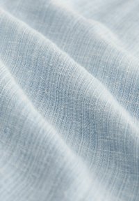 Light blue fabric with a smooth, textured weave. The material features fine, uniform lines and a subtle, soft appearance.
