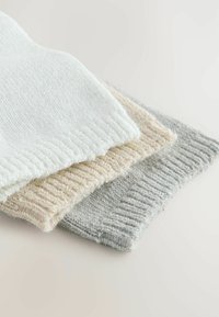 Three knitted fabric swatches in white, beige, and light gray. Each features a textured, ribbed edge with a soft, fuzzy appearance.